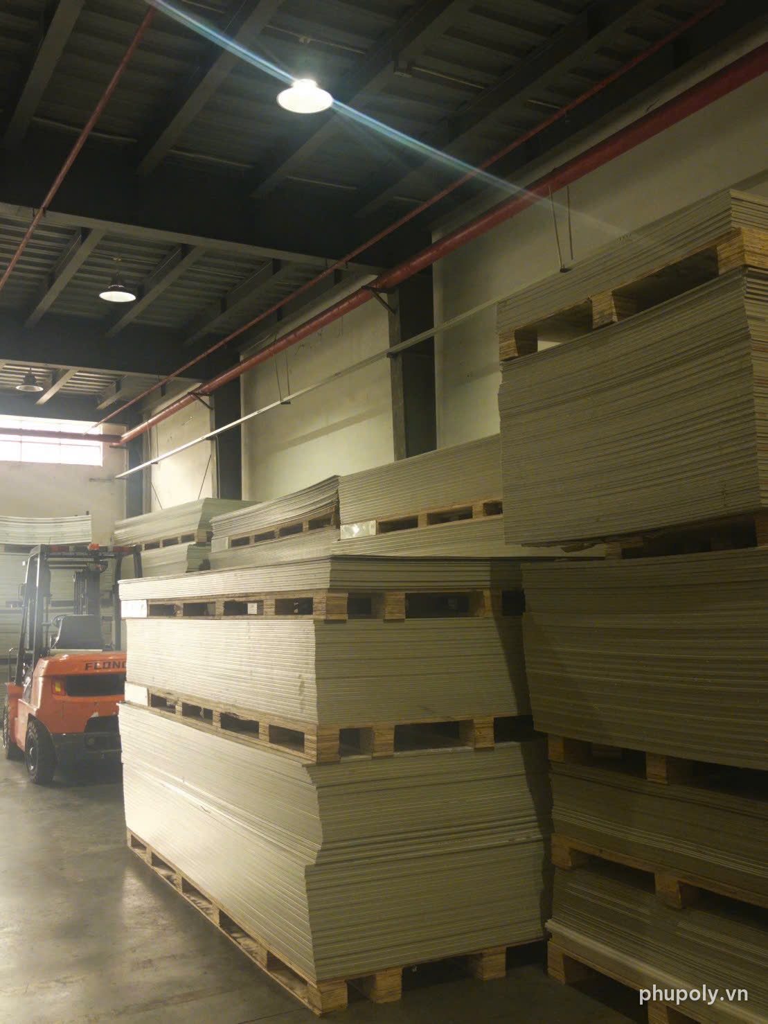 Nhiều chồng tấm nhựa PP vàng be xếp trên pallet trong nhà kho