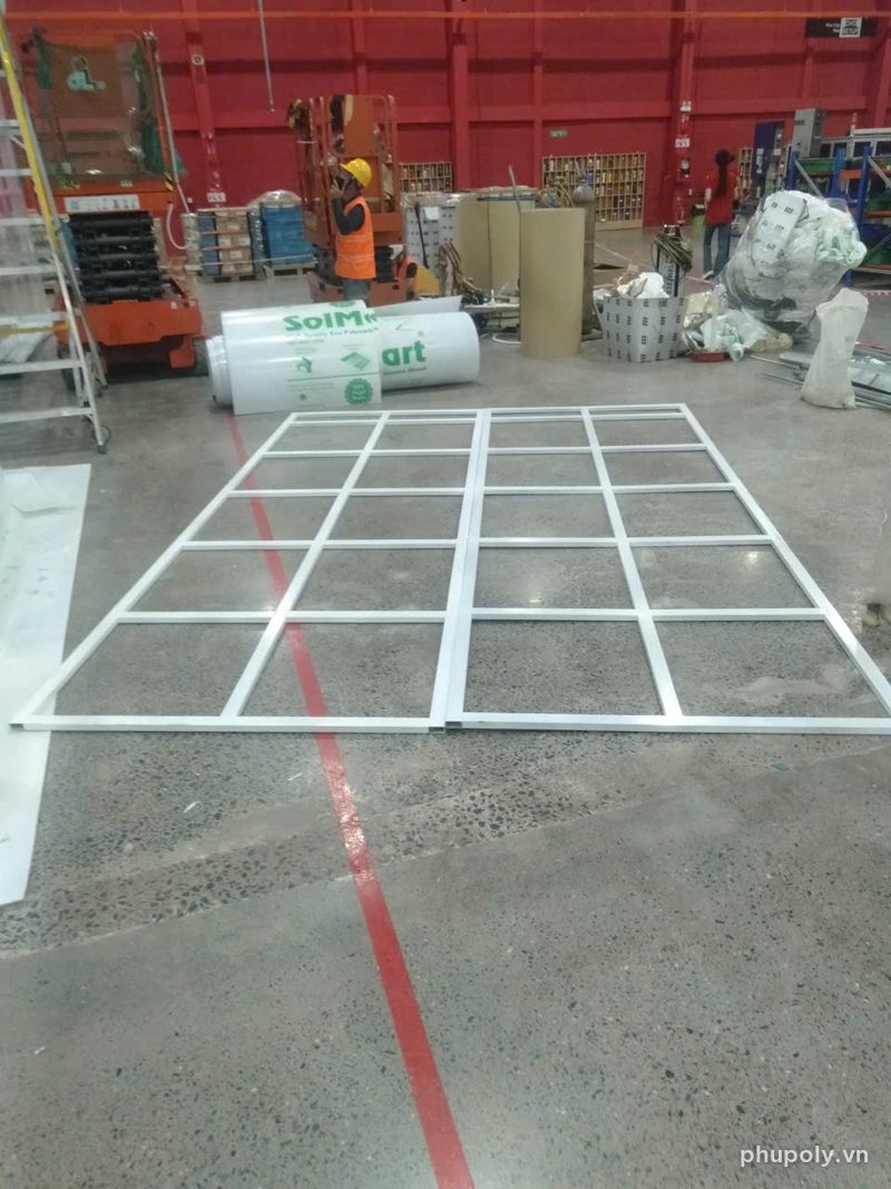 Khung vách thép trắng ô lưới ghép sẵn trên sàn xưởng cạnh hai cuộn poly SolMart
