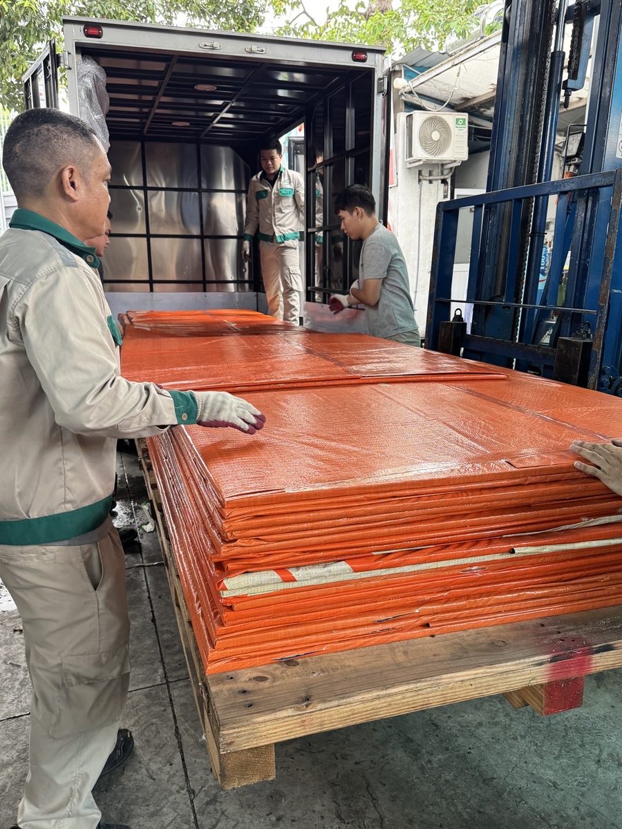 Kiện tấm phẳng poly bọc bạt được chuyển lên xe tải tại kho