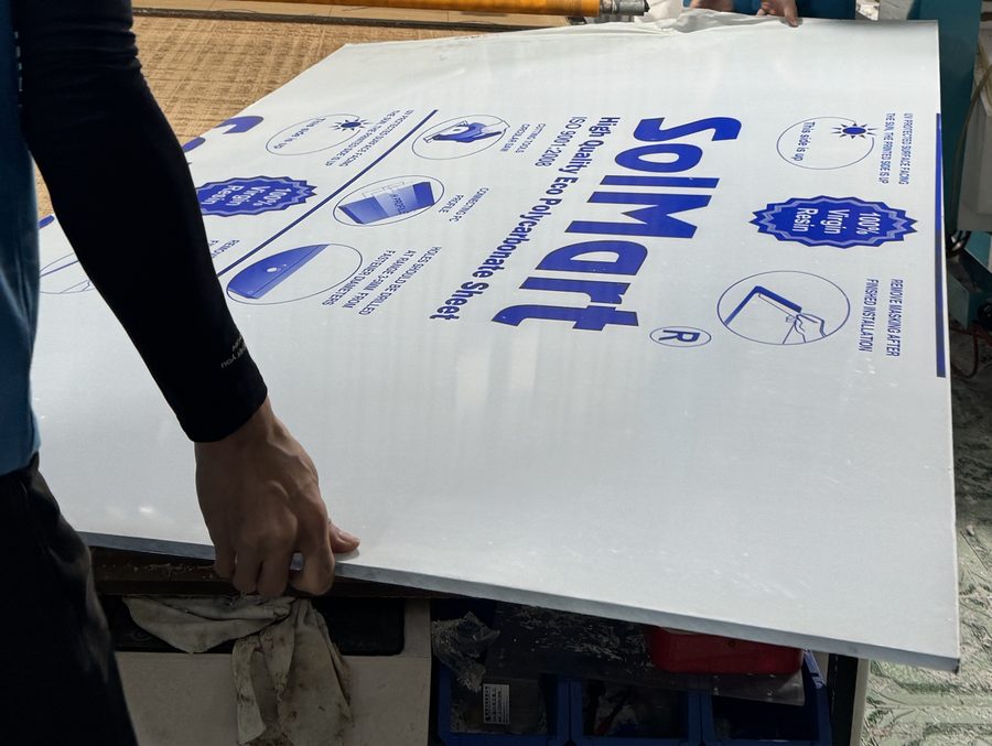 Đặt tấm poly đặc SolMart 5mm lên bàn CNC, giữ nguyên màng bảo vệ