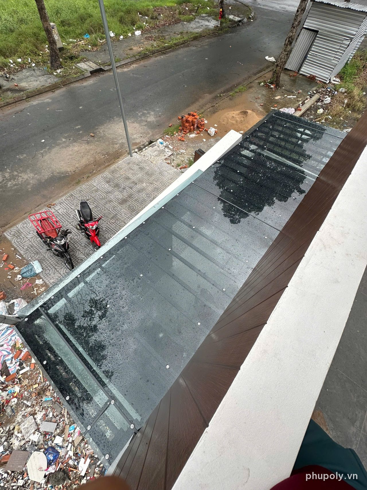 Mái trước nhà phố lợp tấm poly xám khói bắt vít, nhìn từ tầng trên sau mưa