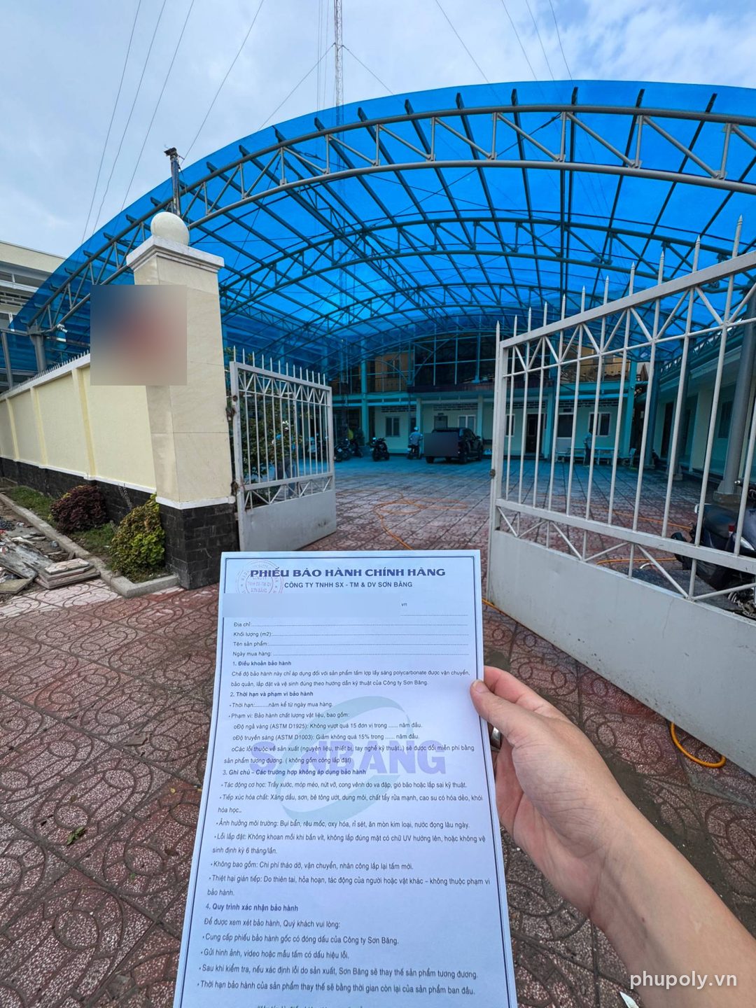 Phiếu bảo hành chính hãng Sơn Băng cầm trước cổng công trình mái vòm poly tosca