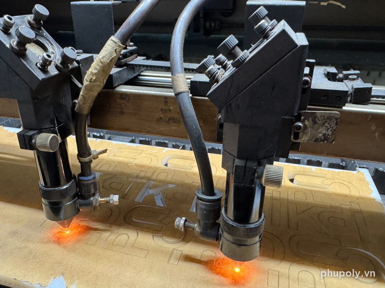 Hai đầu laser đang cắt các chữ trên tấm mica sữa 10mm còn giấy bảo vệ