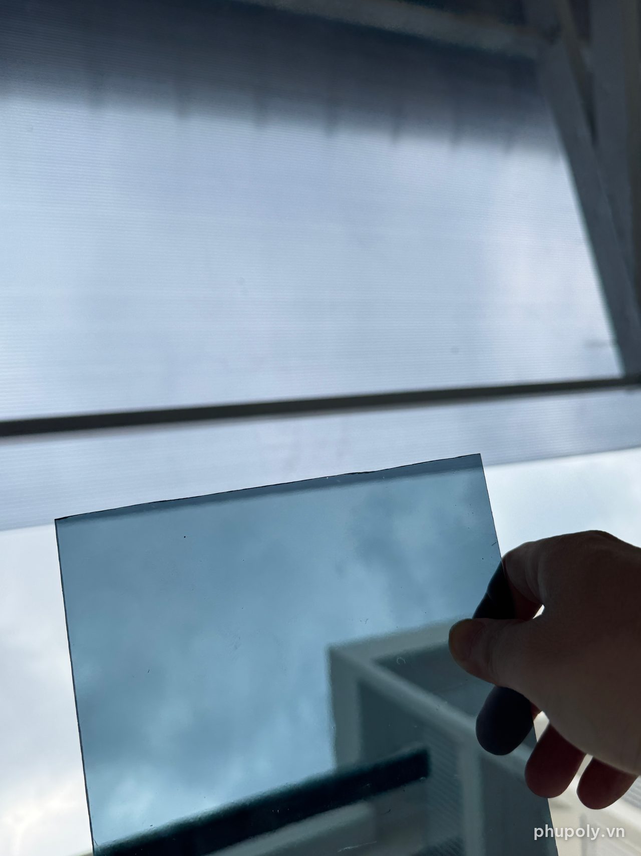 Soi tấm poly đặc xám khói dưới mái poly rỗng cùng màu, nhìn rõ mép toà nhà phía sau