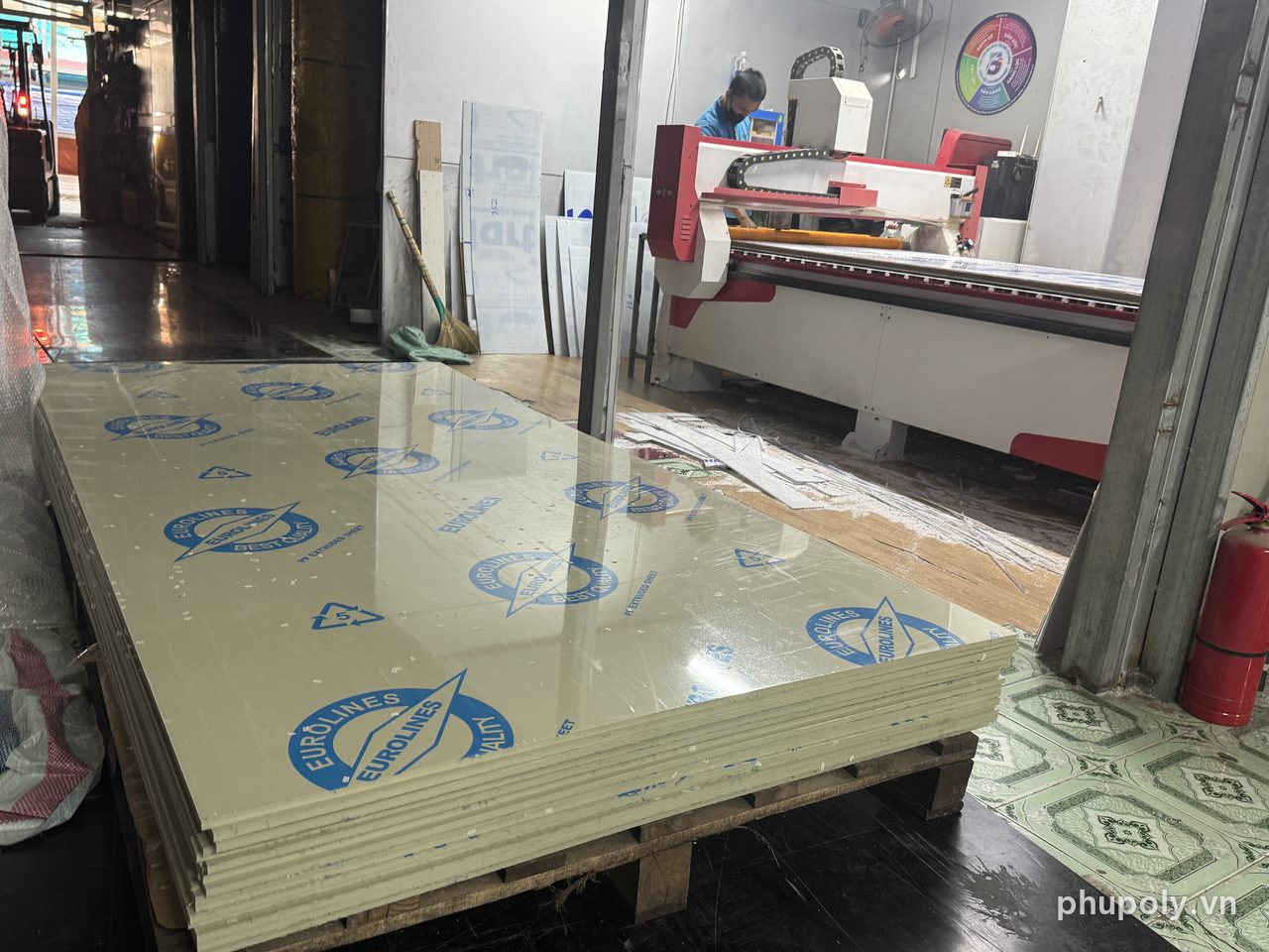 Chồng tấm nhựa PP 10mm vàng be xếp trên pallet, máy CNC phía sau