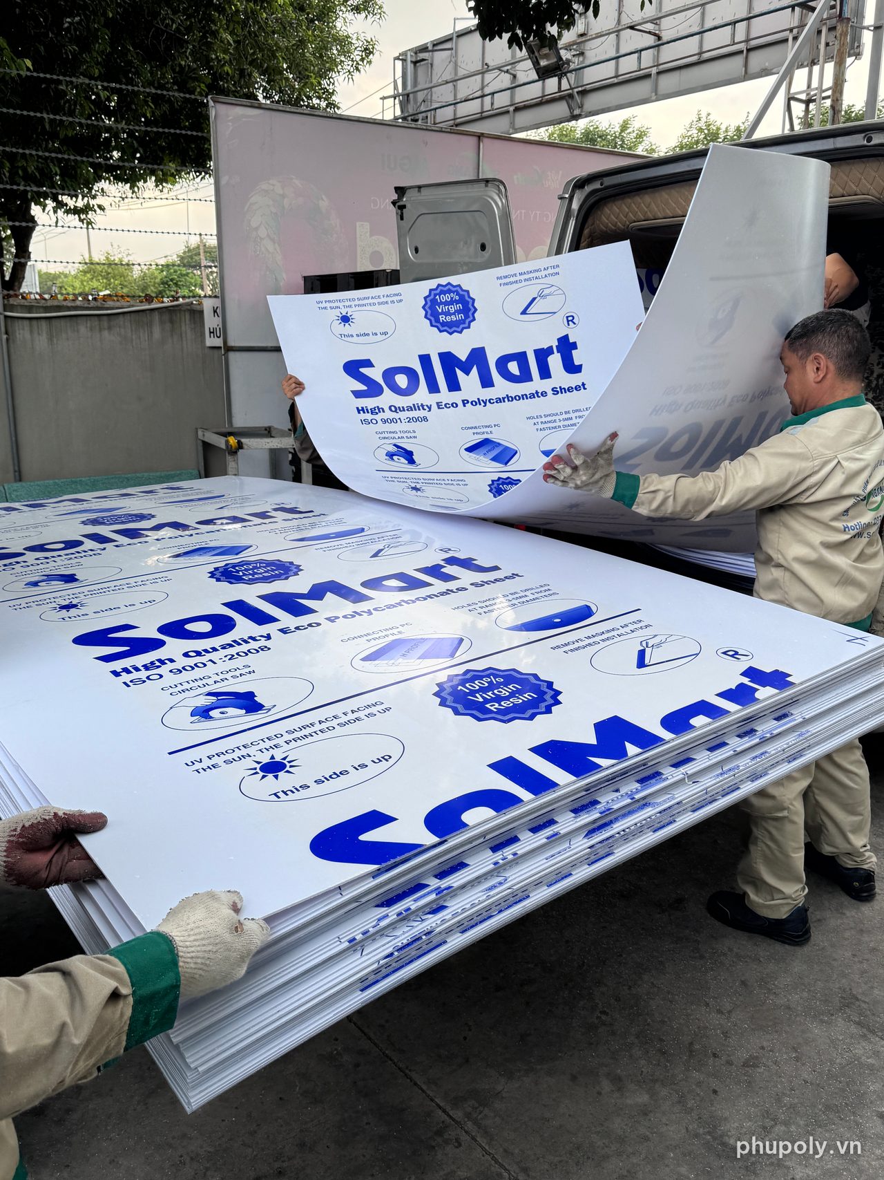 Hai thợ nâng tấm poly đặc trắng sữa dài tại kho, tấm cong theo tay mà không gãy