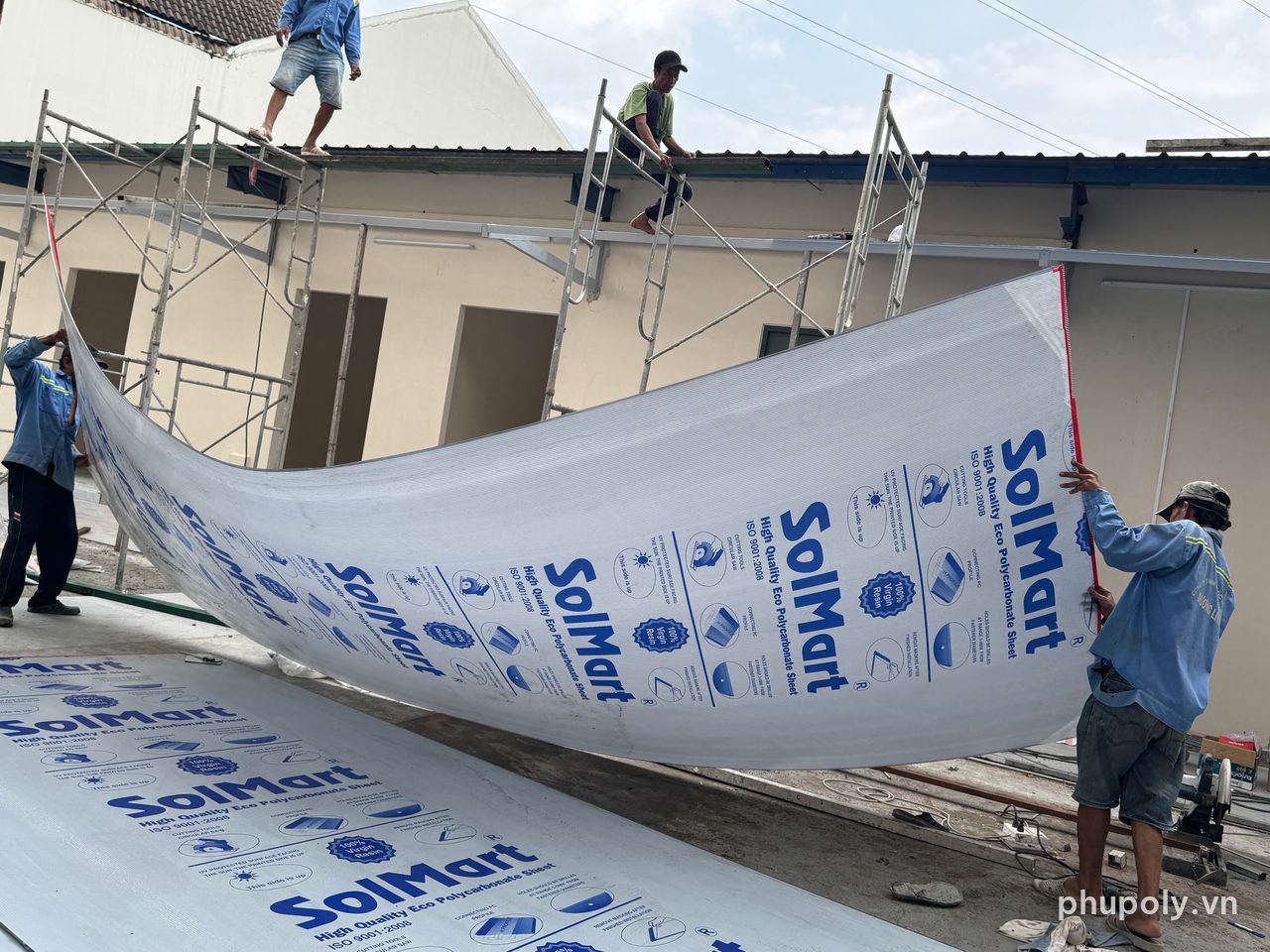 Thợ đưa tấm poly rỗng SolMart xám khói lên khung mái che lối đi