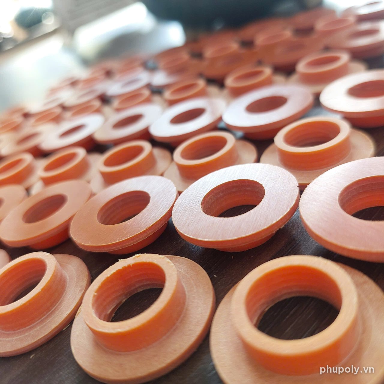 Vòng đệm và bạc có mép gia công CNC từ tấm phíp, bày trên bàn